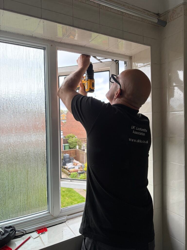 Technician using a drill to repair an open UPVC casement window