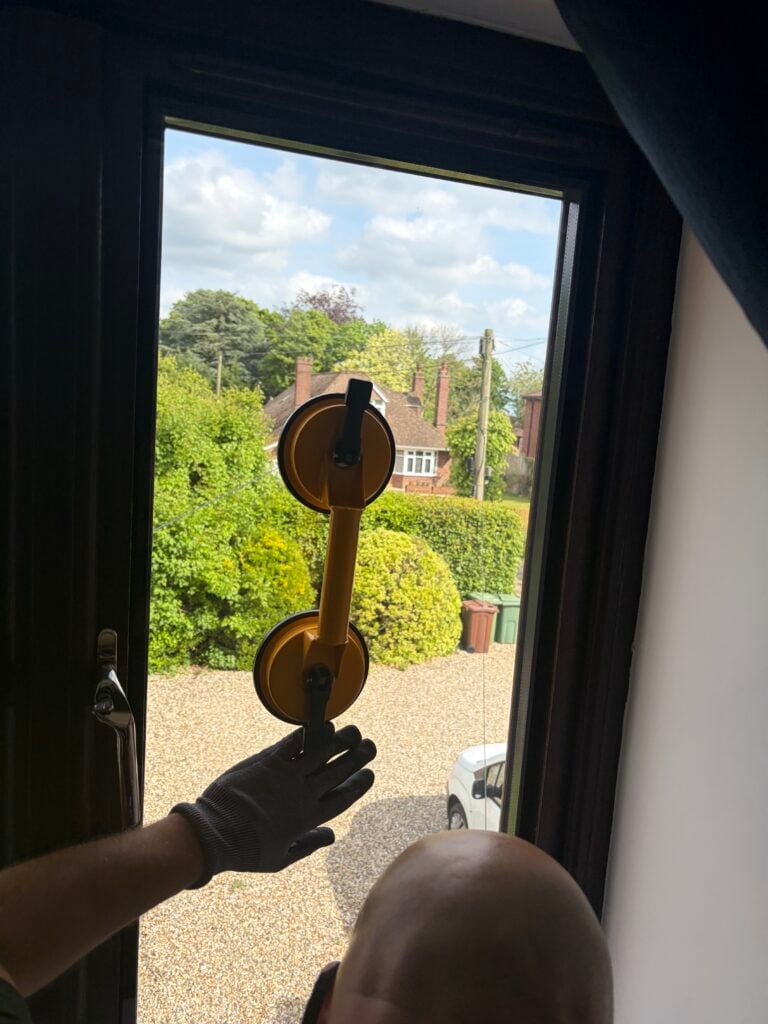 Technician holding a window glass pane with a double suction lifter
