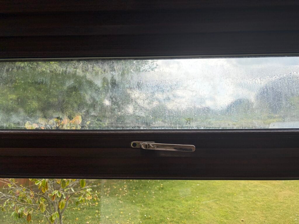 Condensation obscuring the upper pane of a woodgrain window
