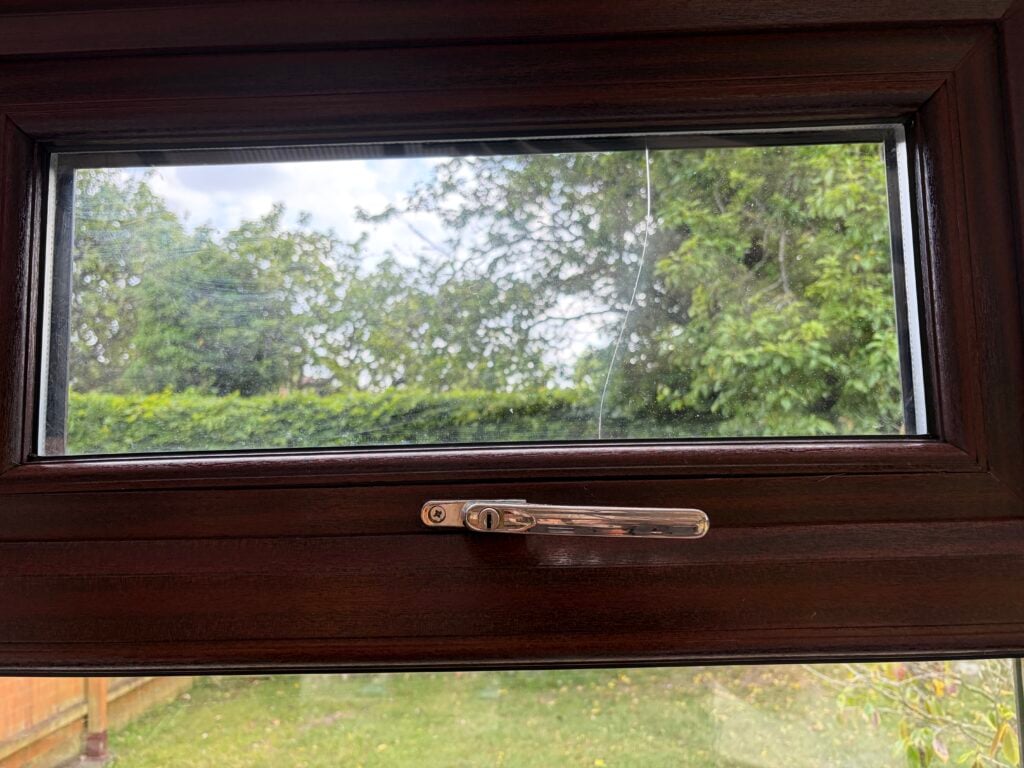 Crack running through the glass of a woodgrain casement window