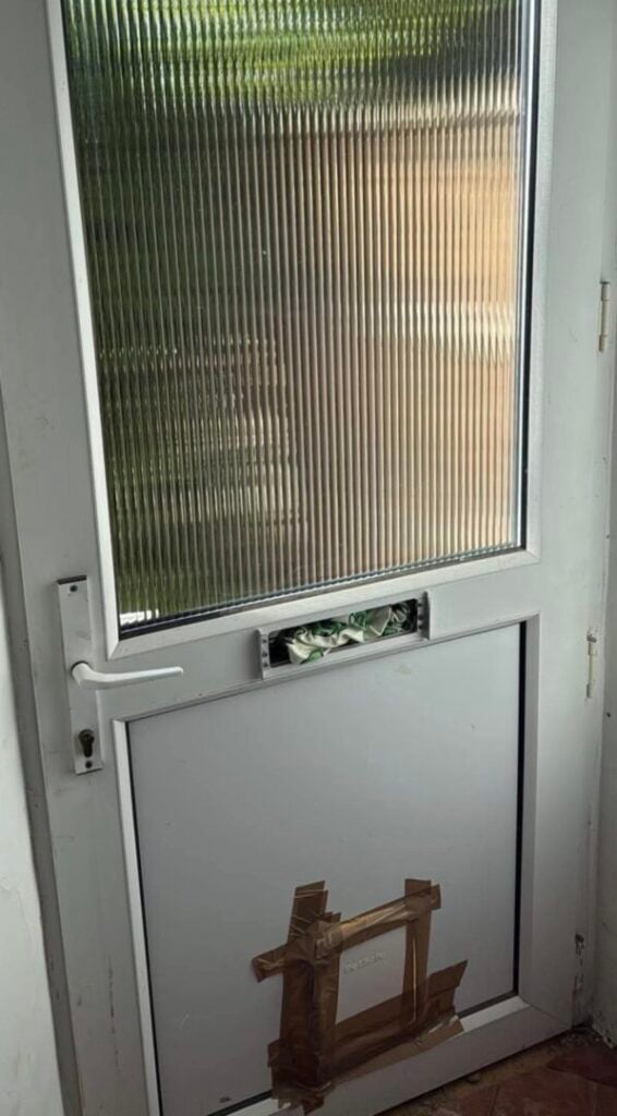 White UPVC door with an exposed letterbox opening and taped lower panel