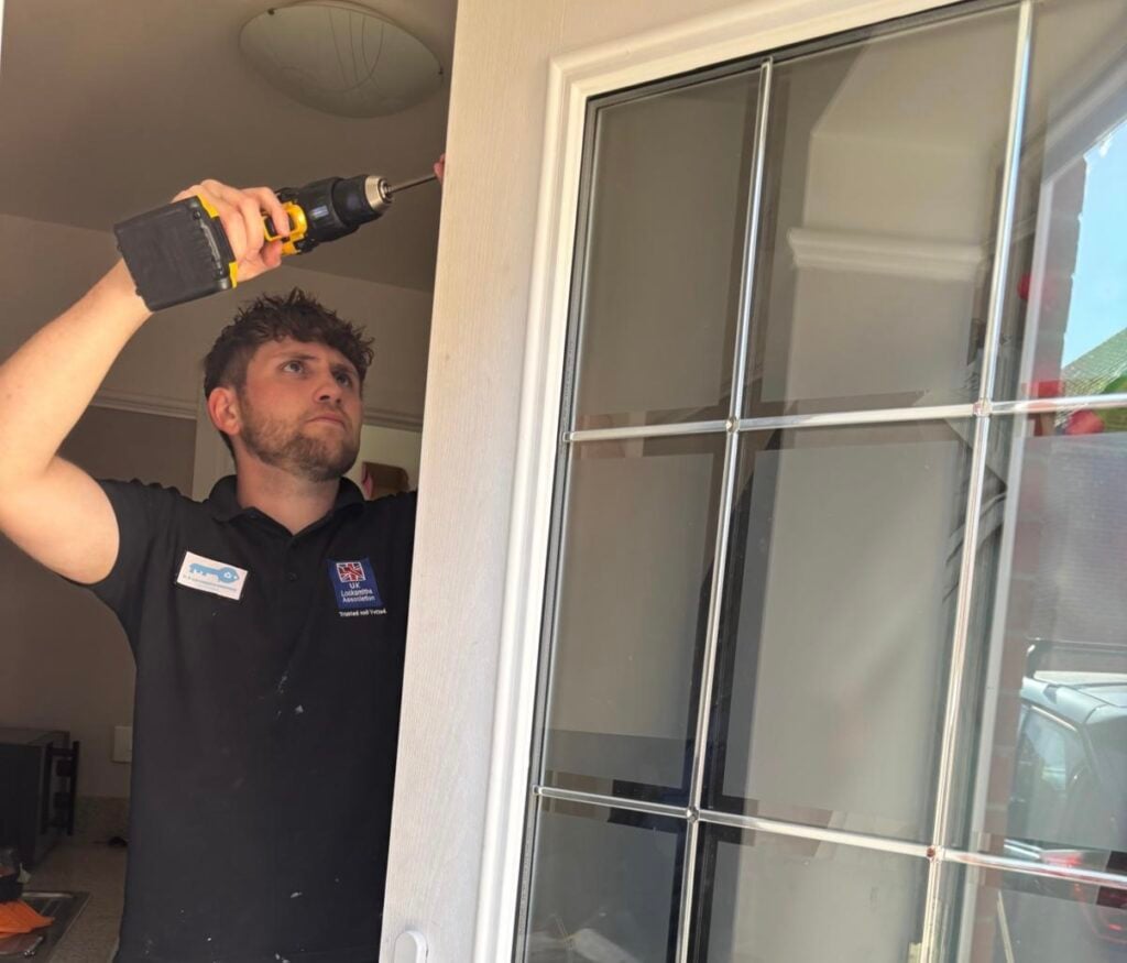 BC Locksmith technician using a drill on a white glazed door