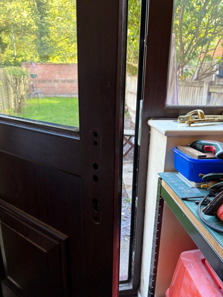Woodgrain door with its handle removed and fixing holes exposed