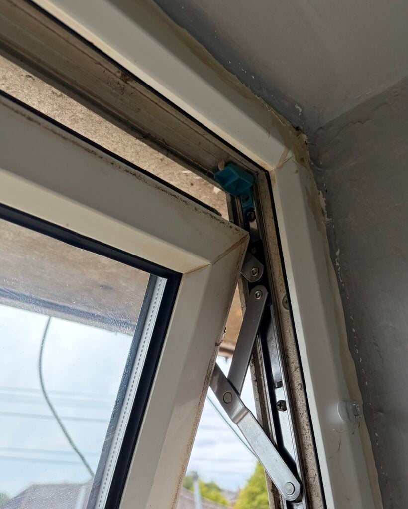 Metal friction hinge inside the corner of an open UPVC window