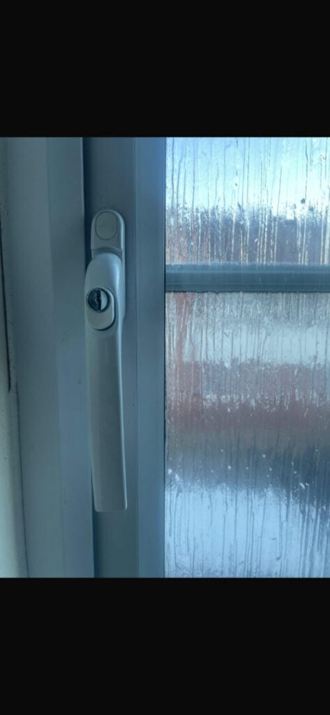White locking handle pointing down on a closed UPVC window